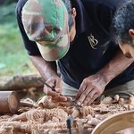 Seseorang sedang membuat kerajinan kriya kayu dan seni patung di bengkel kerja industri kreatif.